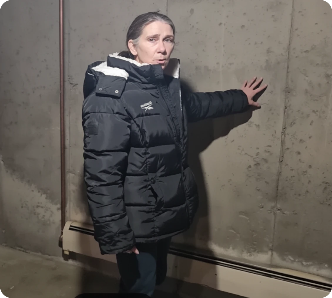 Person in coat touching concrete wall indoors.